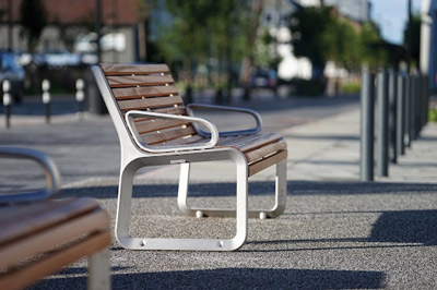 Banc en bois et métal avec dossier et accoudoirs.